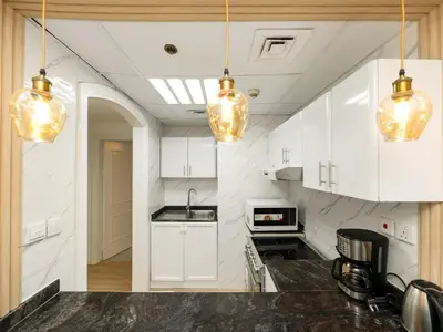 a kitchen with white cabinets and pendant lights at Luxury 3BHK w Floating Bed in Dubai Marina Man 2805 in Dubai