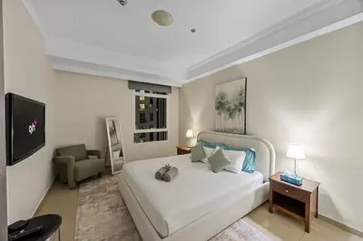 a bedroom with a large white bed and a chair at Elegant 2BR - Stunning Sea Views & Prime Location in Dubai