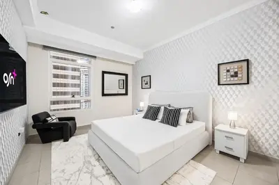 a white bedroom with a white bed and a chair at Elegant 2BR - Stunning Sea Views & Prime Location in Dubai