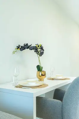 a table with two plates and a vase with flowers at PVH - Modern 1BR Near Metro - Alexis Tower in Dubai