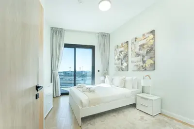 a white bedroom with a large bed and a window at PVH - Modern 1BR Near Metro - Alexis Tower in Dubai