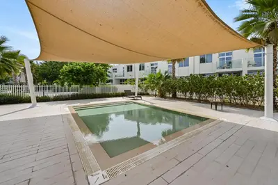 a swimming pool with a large umbrella over it at Modern 1 Bedroom Apartment in Damac Hills 2 in Dubai