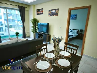 a dining room with a table and a couch at Modern 1BR Apartment with Pool & Gym, 15 Min to JBR in Dubai
