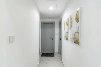 a hallway with white walls and paintings on the walls at Dubai Marina - 2BHK Luxurious Apartment in Dubai