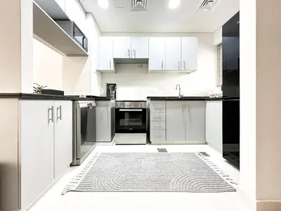 a kitchen with white cabinets and a rug on the floor at Stylish 3BR Retreat Bright Interiors Townhouse Comfort in Dubai