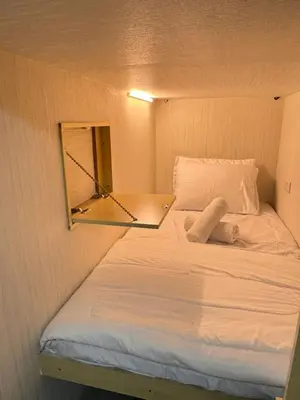 a bed in a small room with a mirror at Luxury Private Capsule Room near Business Bay Downtown in Dubai