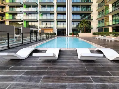 a swimming pool in front of a building at A Signature Living Experience Luxury One-Bedroom in Binghatti Emerald, JVC, Dubai in Dubai