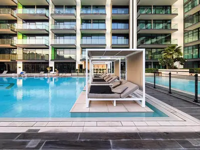 a hotel swimming pool with a lounge chair in front of a building at A Signature Living Experience Luxury One-Bedroom in Binghatti Emerald, JVC, Dubai in Dubai