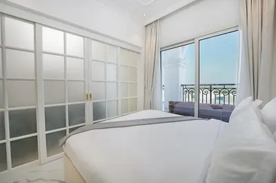 a bedroom with a white bed and a large window at EasyGo- Luxury Living with Resort Facilities and Amenities in Dubai