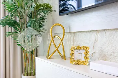 a gold console table with a mirror and a plant at Bloomfields Cozy 1Br Binghatti House in Dubai