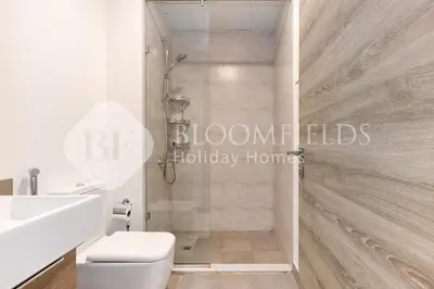 a bathroom with a shower with a toilet and a sink at Bloomfields Spacious 1br Bloom Tower in Dubai