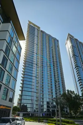 two tall buildings with cars parked in front of them at High Floor, Few Steps From Dubai Canal and Waterfront Promenade, Sobha Hartland Waves, Sobha Hartland by Deluxe Holiday Homes in Dubai