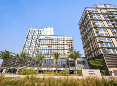 two tall buildings with palm trees in front of them at New Luxury 1 Bed - Opposite Dubai Hills Mall in Dubai