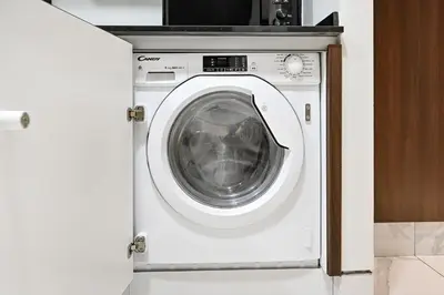 a washing machine in a kitchen with its door open at Stylish Apartment with Balcony and Pool, Close to Dubai's Top Landmarks in Dubai