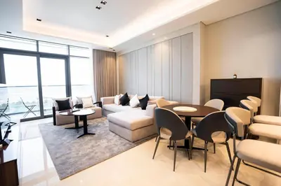 a living room with a couch and a table and chairs at Cityscape Retreat Nobles 2BR Nobles Edition in Dubai