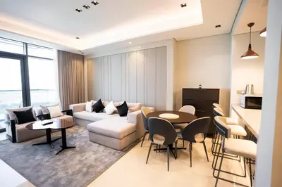 a living room with a couch and a table and chairs at Cityscape Retreat Nobles 2BR Nobles Edition in Dubai