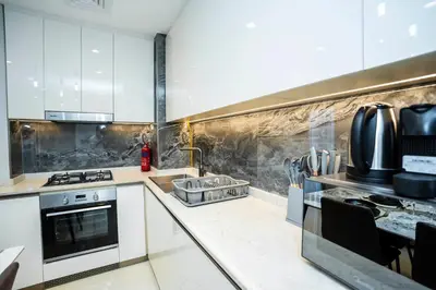 a kitchen with white cabinets and a stove top oven at Luxury 1BR in Nobles Tower Business Bay in Dubai