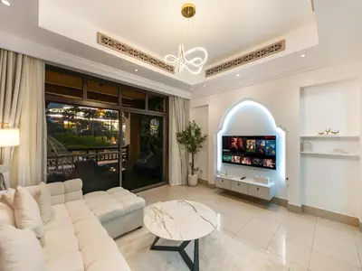 a living room with a white couch and a tv at Luxury 2BR- Pool with Burj View- 2 Min to Dubai Mall in Dubai