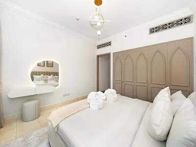 a white bedroom with a large bed and a chandelier at Luxury 2BR- Pool with Burj View- 2 Min to Dubai Mall in Dubai