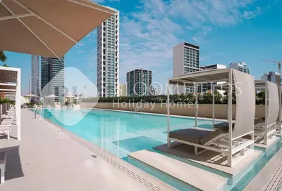 a swimming pool with a chaise lounge and a city skyline at Bloomfields Modern 1Br Binghatti Onyx in Dubai