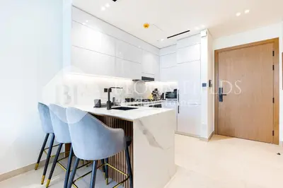 a kitchen with white walls and a bar with stools at Bloomfields Modern 1Br Binghatti Onyx in Dubai