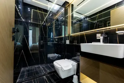 a black tiled bathroom with a toilet and a sink at Smart Home 1BR with Pool and City View in JVC by Bhavan Vacation Homes in Dubai