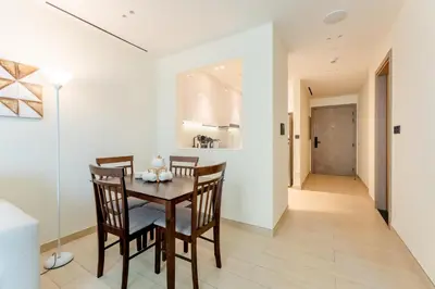 a dining room with a table and chairs and a hallway at Smart Home 1BR with Pool and City View in JVC by Bhavan Vacation Homes in Dubai