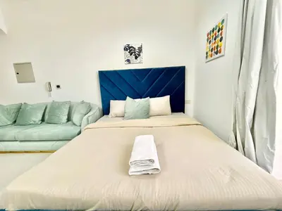 a bedroom with a large bed and a couch at Homes2Retreat - Modern Studio with Balcony in JVT in Dubai