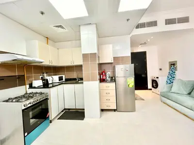a kitchen with a refrigerator and a couch in a room at Homes2Retreat - Modern Studio with Balcony in JVT in Dubai