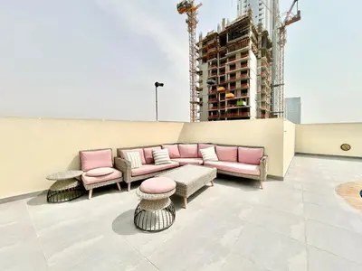 a rooftop patio with pink furniture and a building at Homes2Retreat - Modern Studio with Balcony in JVT in Dubai