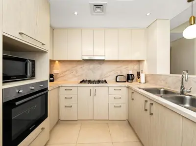 a kitchen with white cabinets and a sink and a microwave at Kensington 2BR walk to Dubai Mall via Link in Dubai