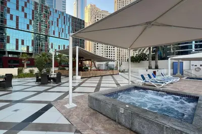 a swimming pool with chairs and umbrellas on a building at Panoramic Marina Views Walk to Beach and JBR 1BR in Dubai