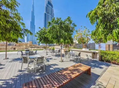 a patio with tables and chairs and trees and buildings at Stylish & Comfy Downtown Oasis Views, Pool & Gym in Dubai