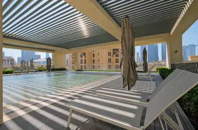 a swimming pool with a umbrella and a chair and a swimming pool at Stylish & Comfy Downtown Oasis Views, Pool & Gym in Dubai