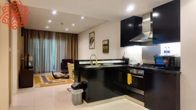a kitchen with black appliances and a living room at Amazing 1bdr apartment in business bay in Dubai