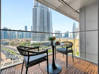 a balcony with a table and chairs and a view of a city at Kensington 1BR and Study with Sofa Bed Burj View Dubal mall link in Dubai
