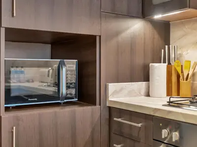 a kitchen with a microwave oven in a cabinet at Kensington 1BR and Study with Sofa Bed Burj View Dubal mall link in Dubai
