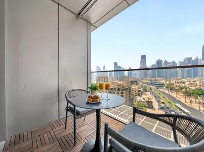 a balcony with a table and chairs and a view of a city at Kensington 1BR and Study with Sofa Bed Burj View Dubal mall link in Dubai