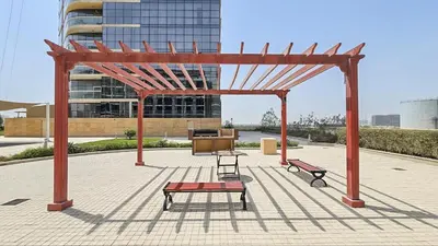 a pavilion with two benches and a table in front of a building at Bright and Cozy 1BHK JVC by Czechin Great Location in Dubai