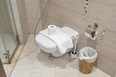 a bathroom with a toilet and a trash can at Bright and Cozy 1BHK JVC by Czechin Great Location in Dubai
