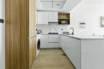 a kitchen with white cabinets and a washer and dryer at BLVD Boutique Style Apartment Gym Pool Balcony JVC in Dubai