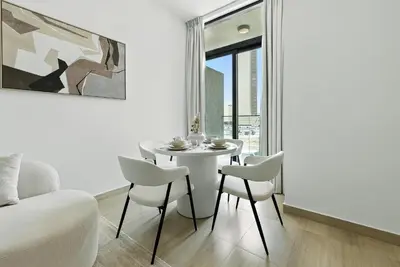 a white dining room with a table and chairs at BLVD Boutique Style Apartment Gym Pool Balcony JVC in Dubai