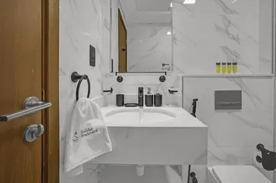 a white bathroom with a sink and a towel at BLVD Boutique Style Apartment Gym Pool Balcony JVC in Dubai
