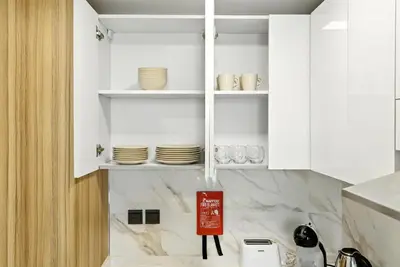 a kitchen with white cabinets and plates on shelves at BLVD Boutique Style Apartment Gym Pool Balcony JVC in Dubai