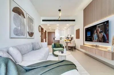a living room with a white couch and a tv at Large 1BR, Pool View, Near Circle Mall, Parking in Dubai