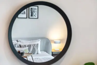 a mirror reflecting a bedroom with a bed and pillows at Family and Group Friendly Near Beach Metro and Marina in Dubai