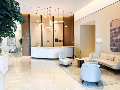 a lobby with a waiting area with chairs and a reception desk at High-Rise Apartment by Burj and Fountain in Dubai