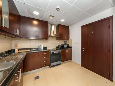 a kitchen with wooden cabinets and a sink and a stove at Comfy 2BR Amwaj 4 Sleeps 10 in Dubai
