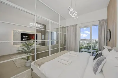 a bedroom with a large white bed and a window at Modern 2BR Golfville Dubai in Dubai