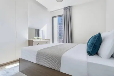 a white bedroom with a large bed with blue pillows at Waterfront 1 BR - Canal View - Fully Furnished - Business Bay - 15 Mins to Dubai Mall and Burj Khalifa in Dubai